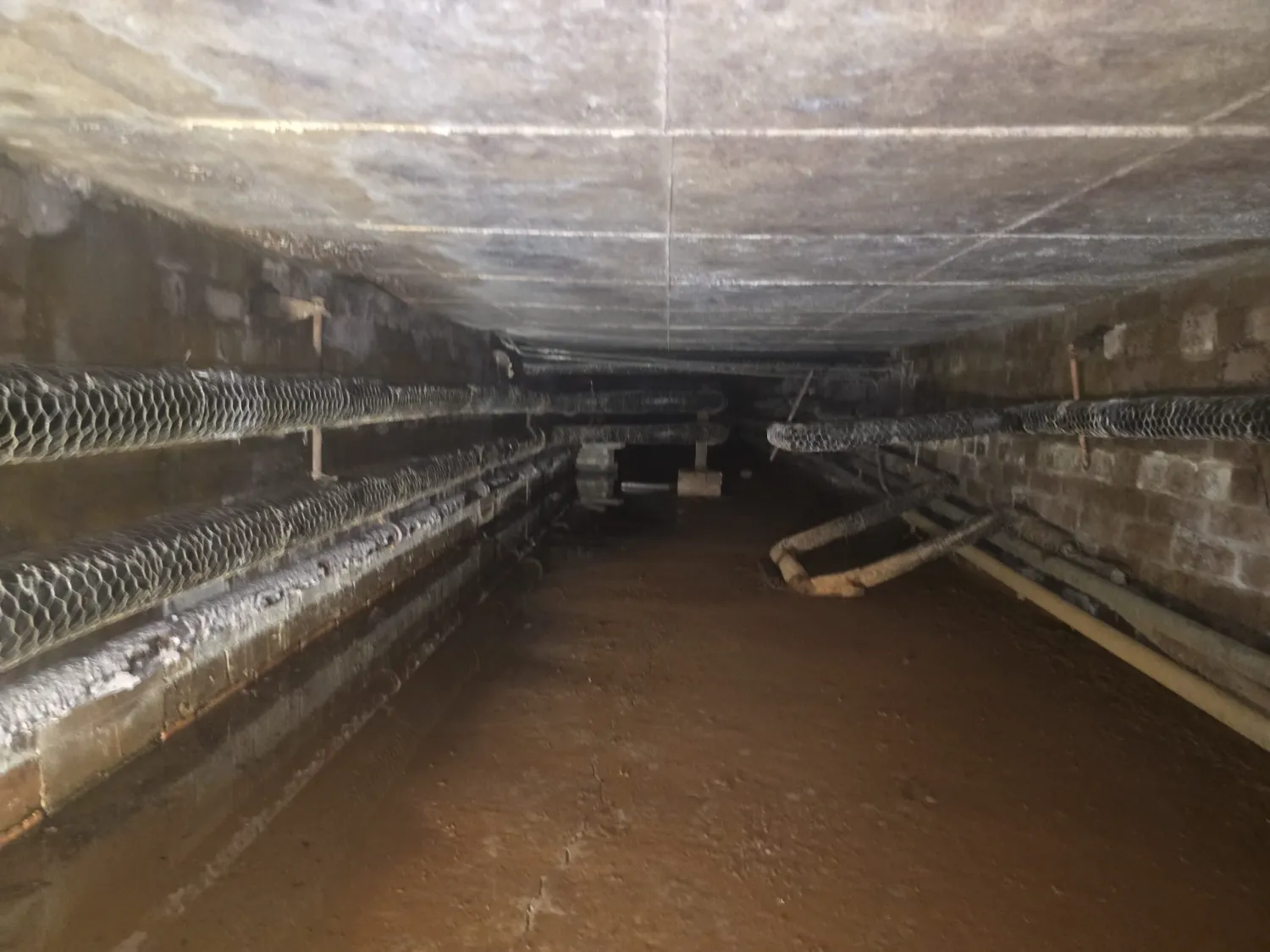 Asbestos thermal pipe insulation on heating pipework inside the underground duct at the Warrington high school
